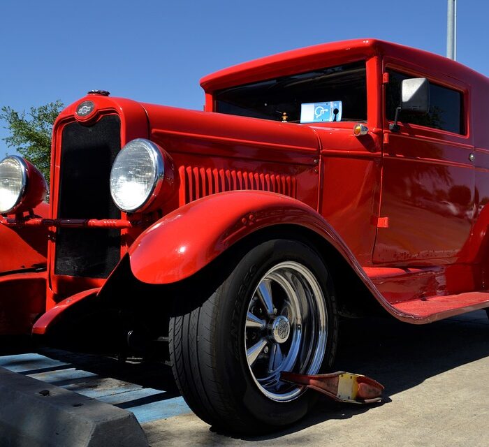 classic car with a boot on the wheel, red car