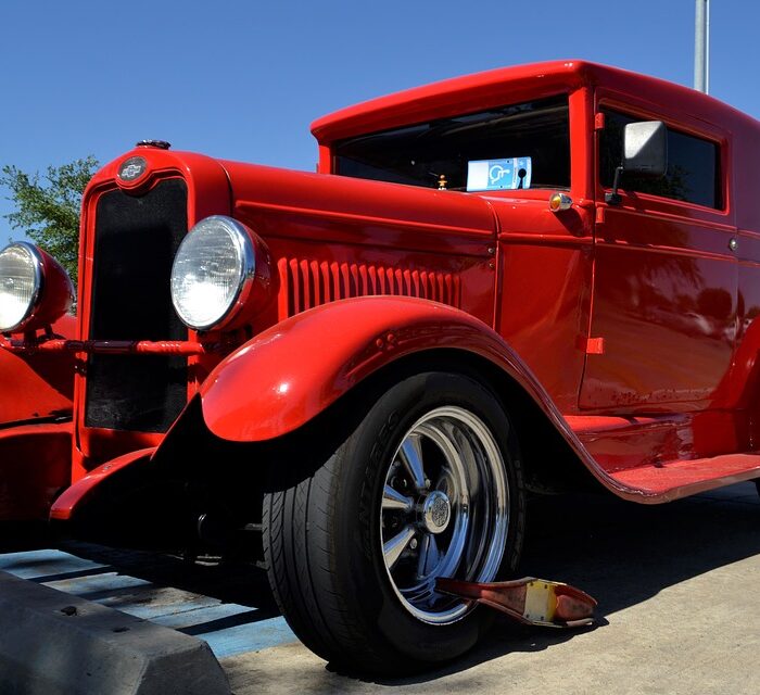 classic car with a boot on the wheel, red car