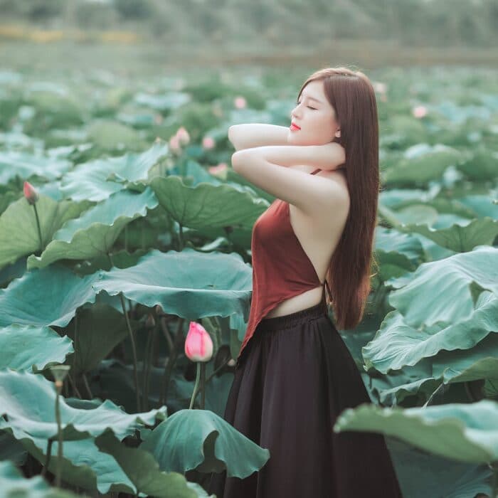 woman surrounded by large leaves in sun, relaxed