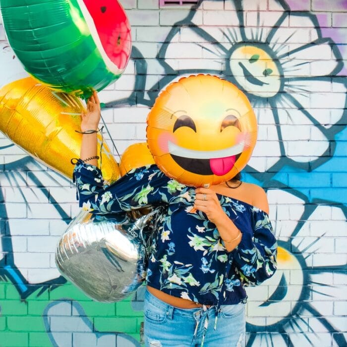 woman holding balloons with emojis emotes