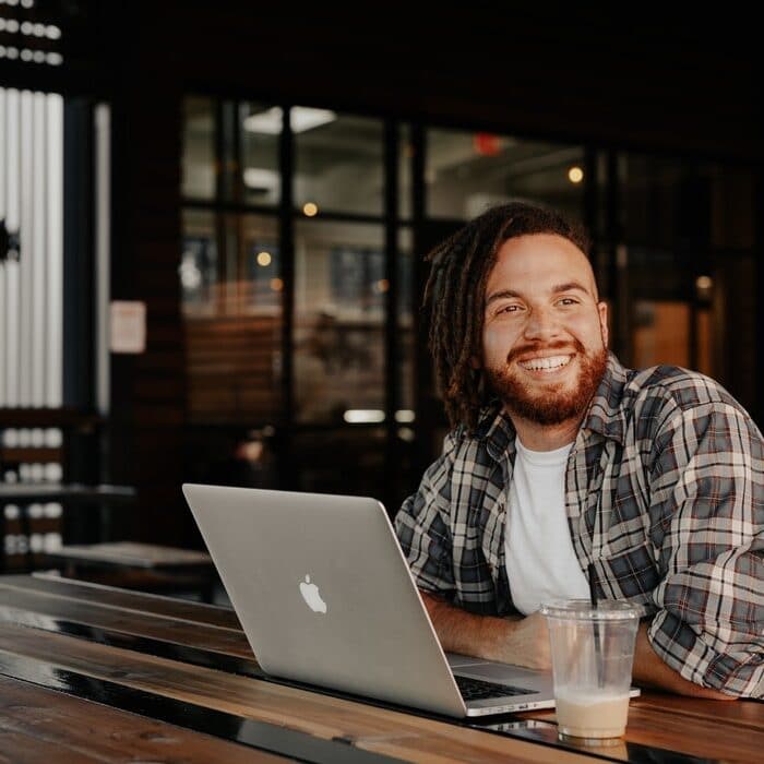 man at a coffee bar on a laptop, dreadlocks