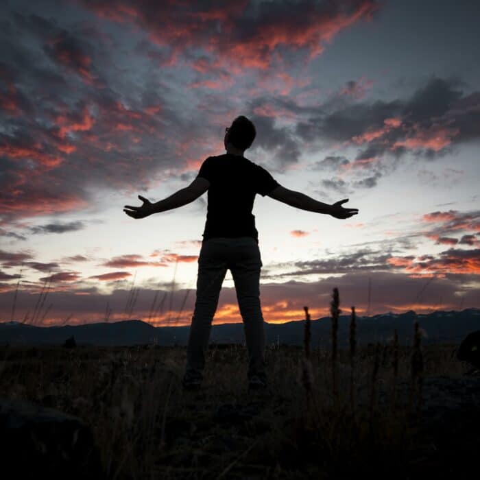 man looking at sky sunset hands out