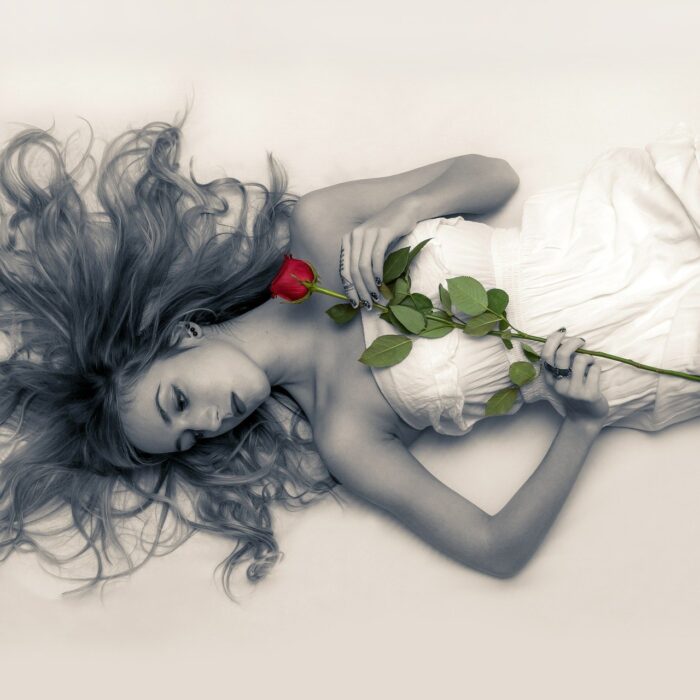 woman laying on the ground with a red rose