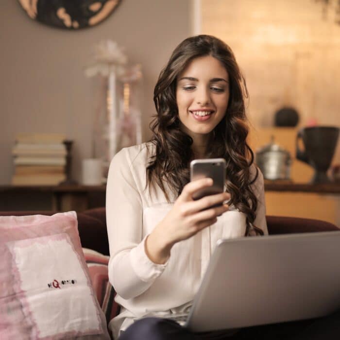 influencer on laptop and phone, smiling