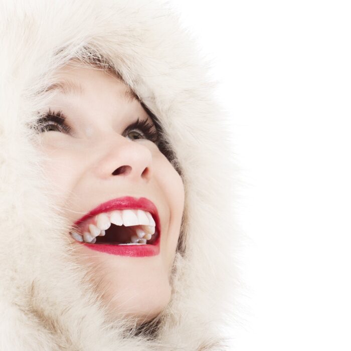 woman smiling at sky wearing a fur coat