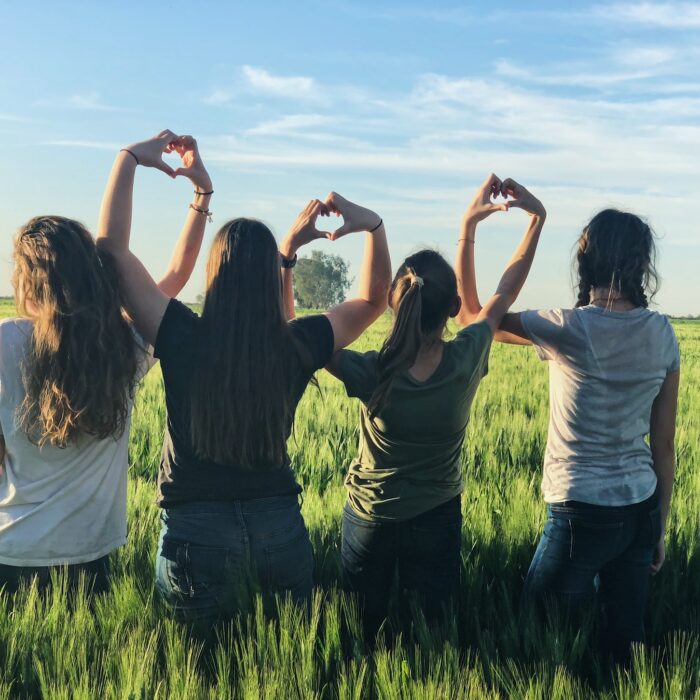 friends with heart hands in a field