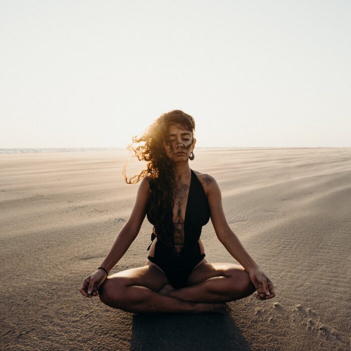 woman meditating in the sand, inflluencer