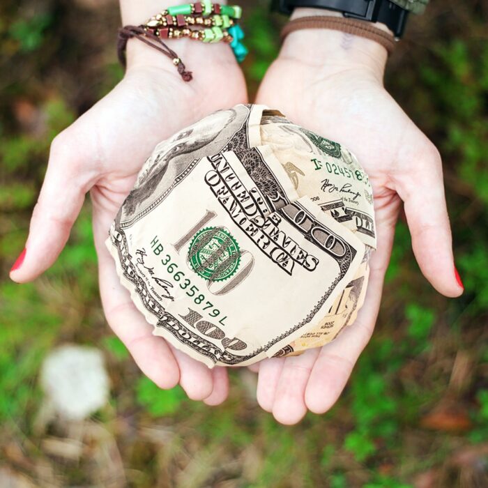 ball of money in two hands with woman holding it