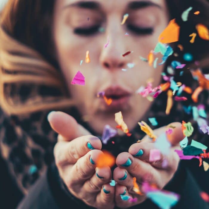 woman blowing confetti into the air