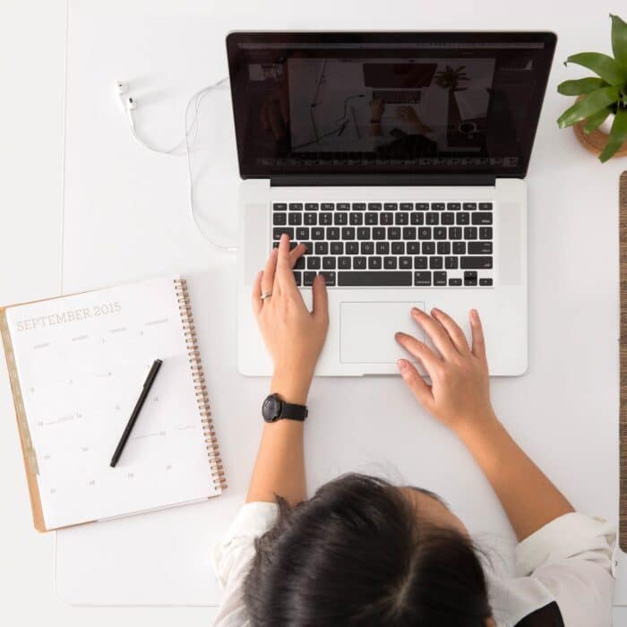 woman on a laptop with tea and calendar planning planner