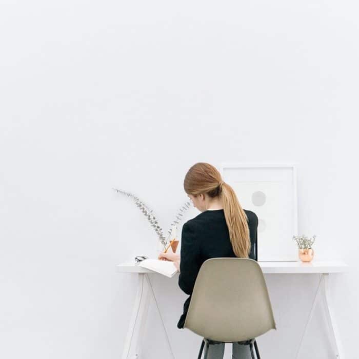 woman writing in a journal in a white room planning