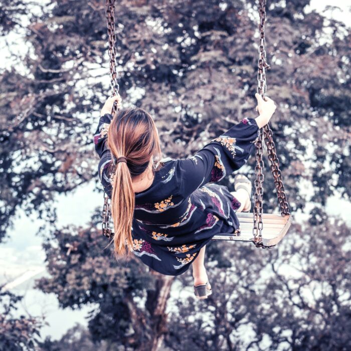 woman on a swing with tree in background