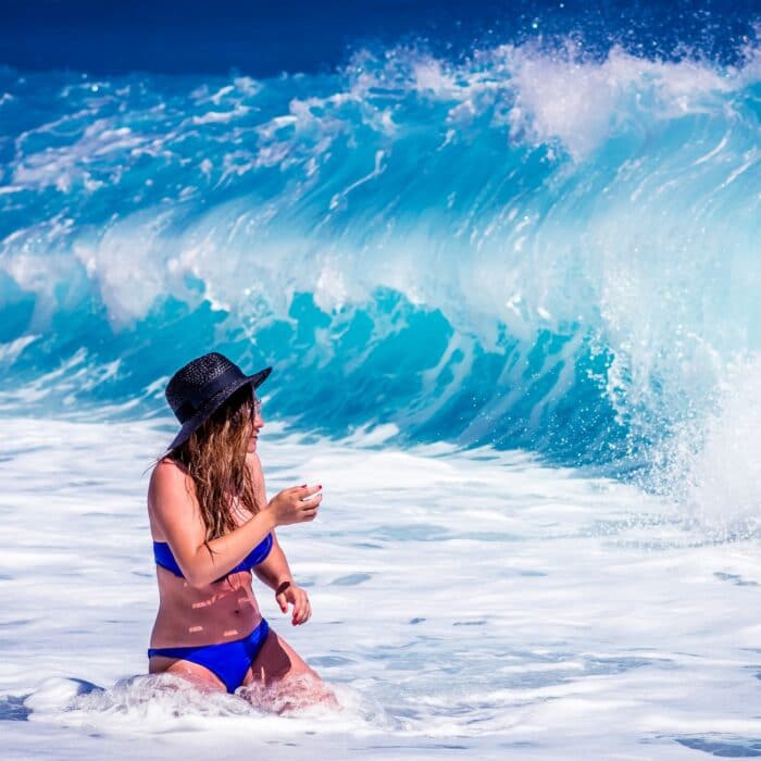 woman in the waves walking bikini bright