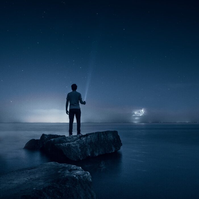 man holding a flashlight at a beach