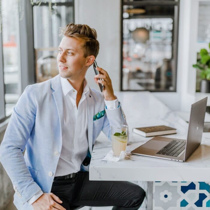 man on laptop with phone at bar