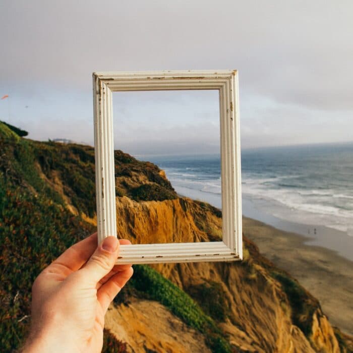 someone holding a picture frame looking at a landscape