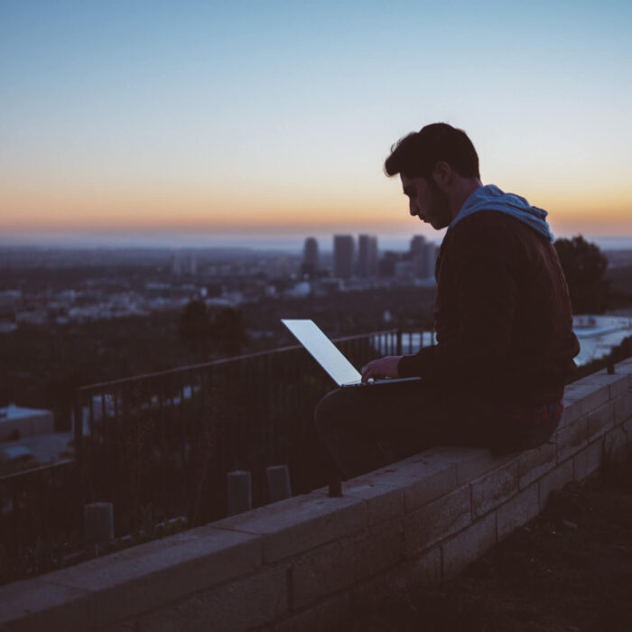 man on laptop sitting on building