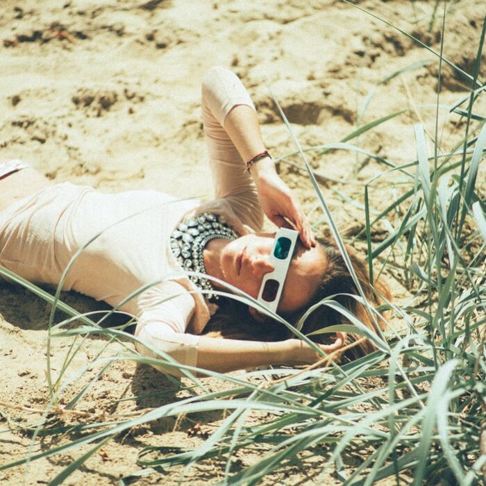 influencer laying on sand wearing 3d glasses woman