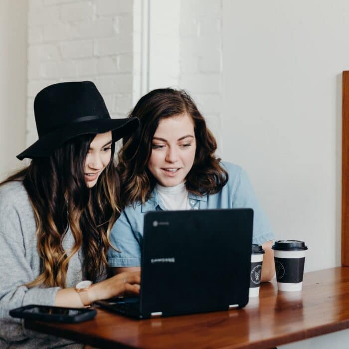 two women on a laptop with coffee
