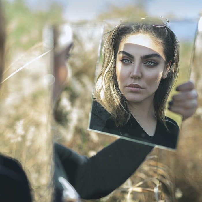 woman holding a mirror in a field