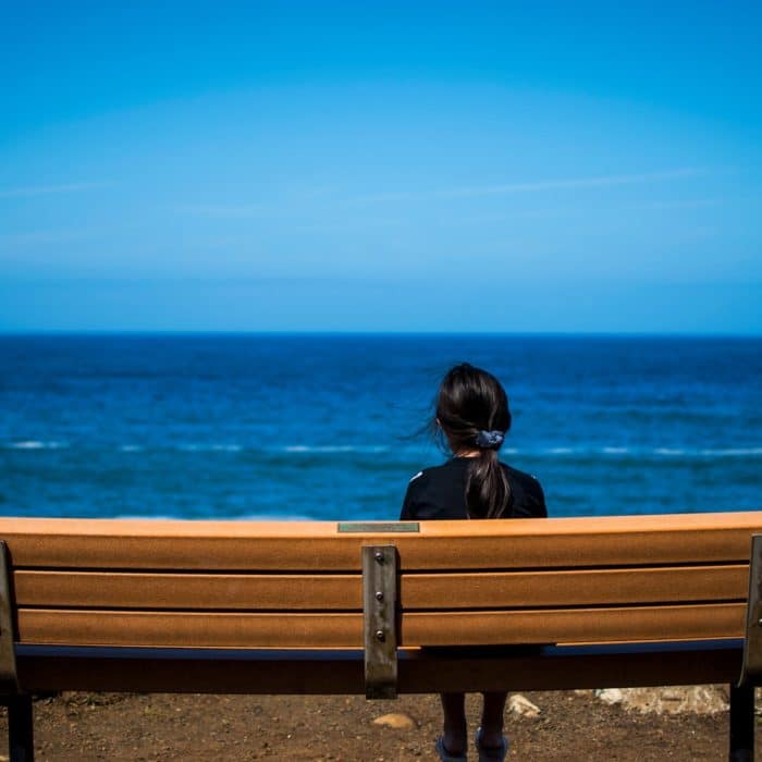 woman looking at ocean on bench