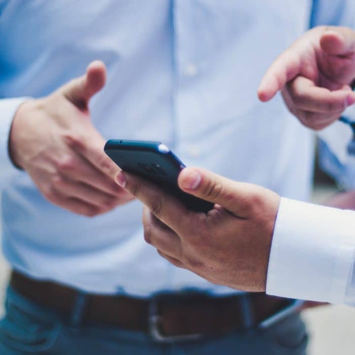 man in blue pointing at phone