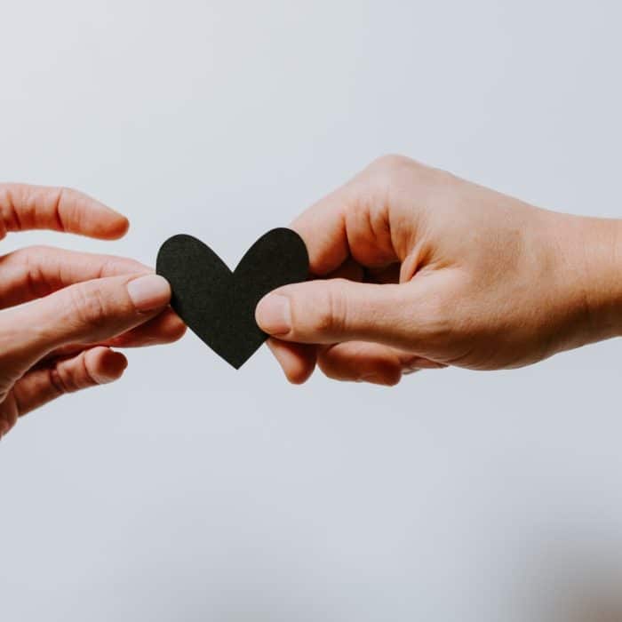 two people holding a black heart