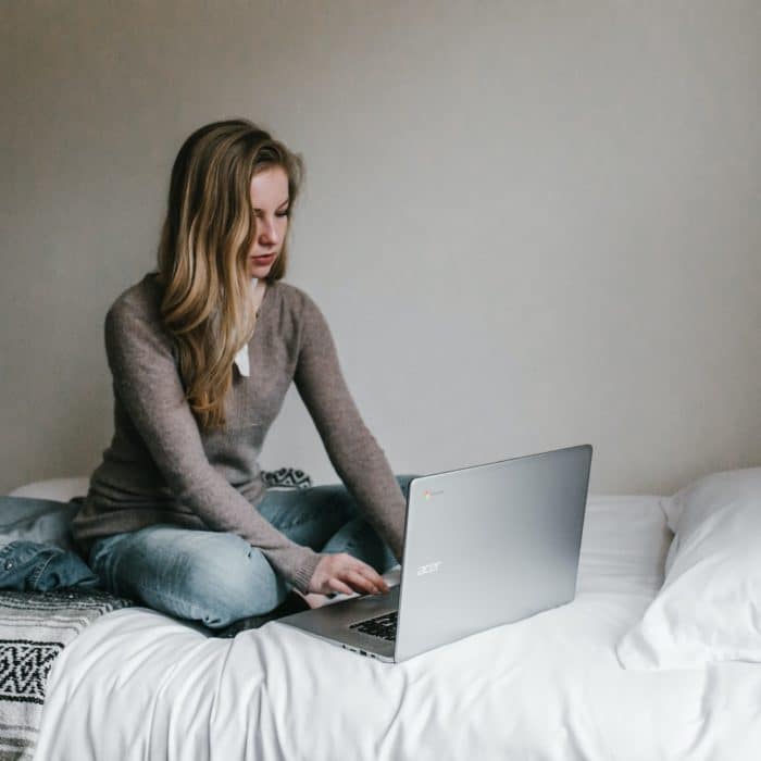 woman sitting on bed on laptop