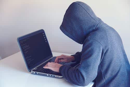 man in hood hacking computer