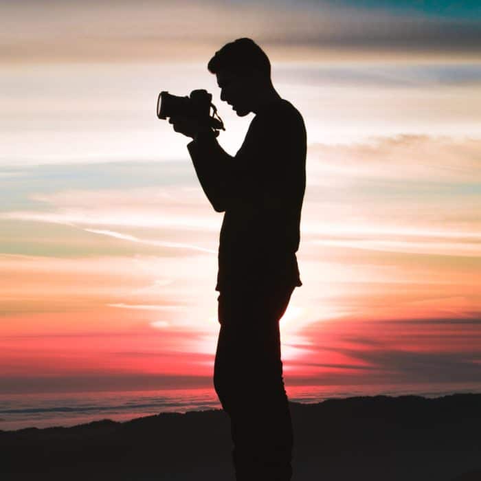 silhoette of man taking pictures against sunset