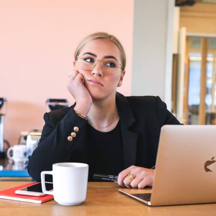 woman in black suit tired at work with laptop