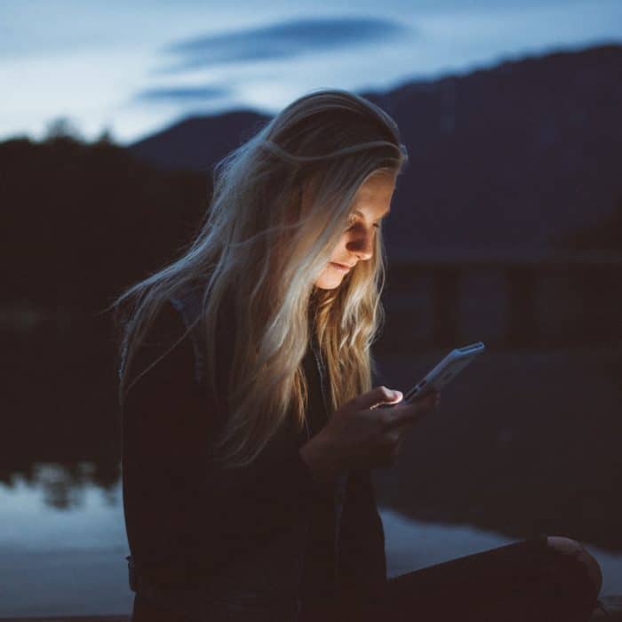 woman looking at phone by water