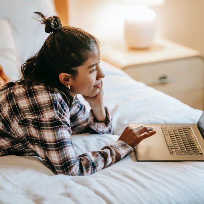 woman on bed browsing computer