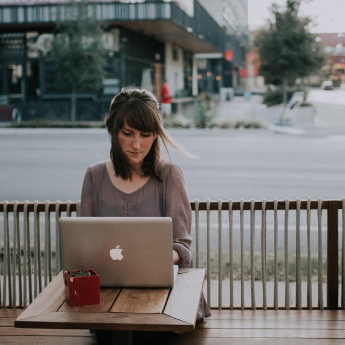 woman working on laptop outside table