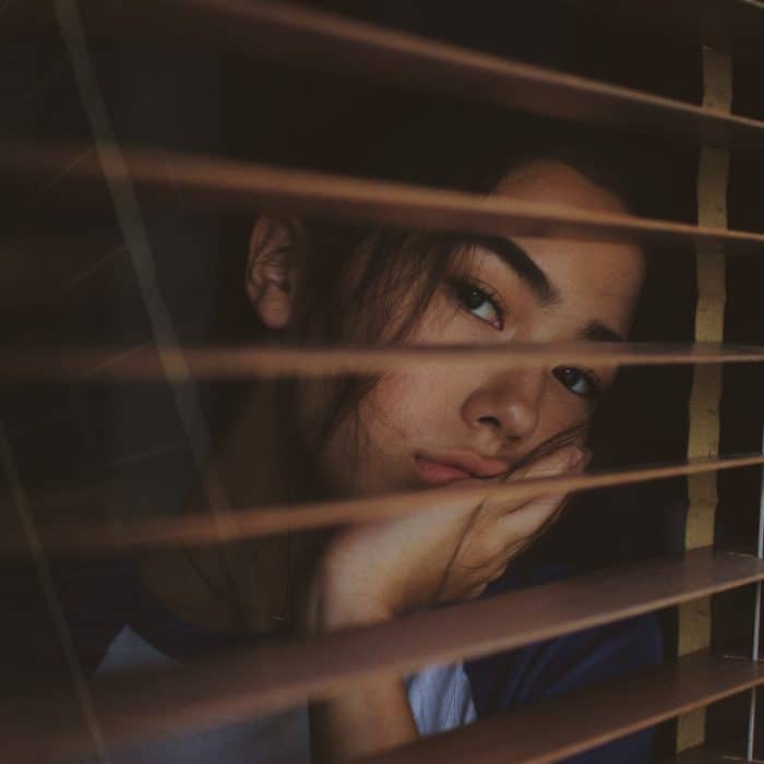 woman looking through blinds