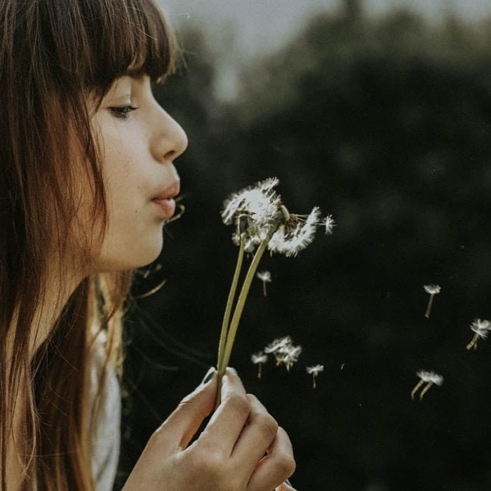 woman blowing on flower