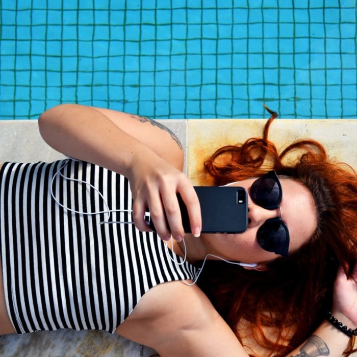 woman laying by pool with phone