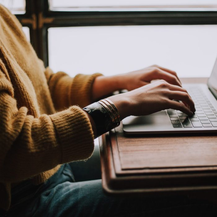 Person Typing on Laptop Sitting at a Table