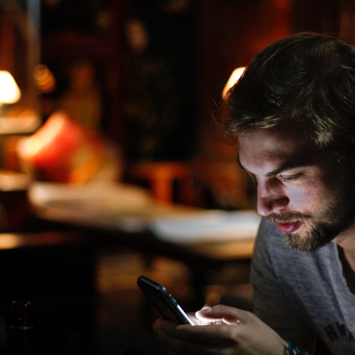 Man Viewing Phone in a Dimly-Lit Room