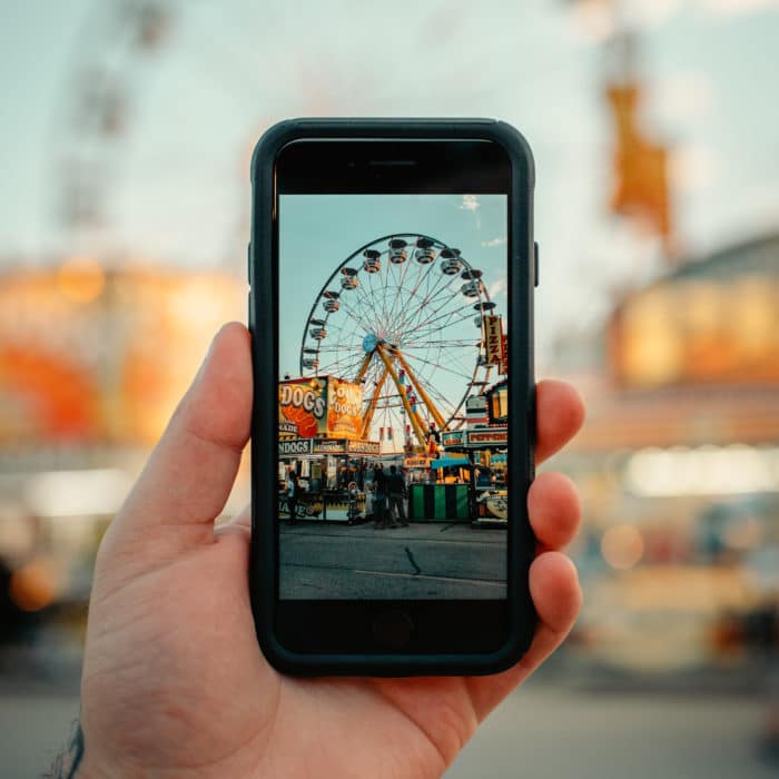 person taking photo of Ferris wheel using phone