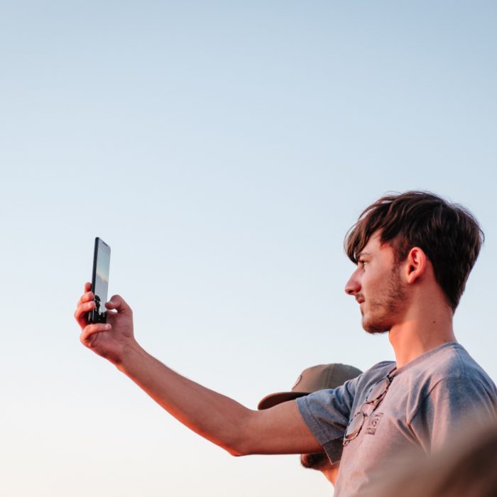 Man Holding Up A Phone While Capturing The Setting Sun