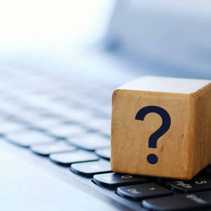 A question mark on a wooden cube on a computer keyboard