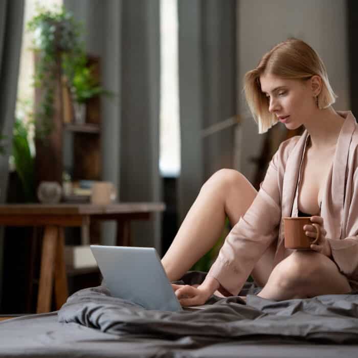 Woman in lingerie using laptop in bed