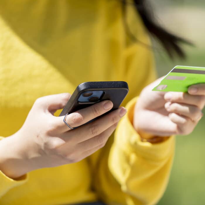 A woman with smart phone buying with credit card online in the park