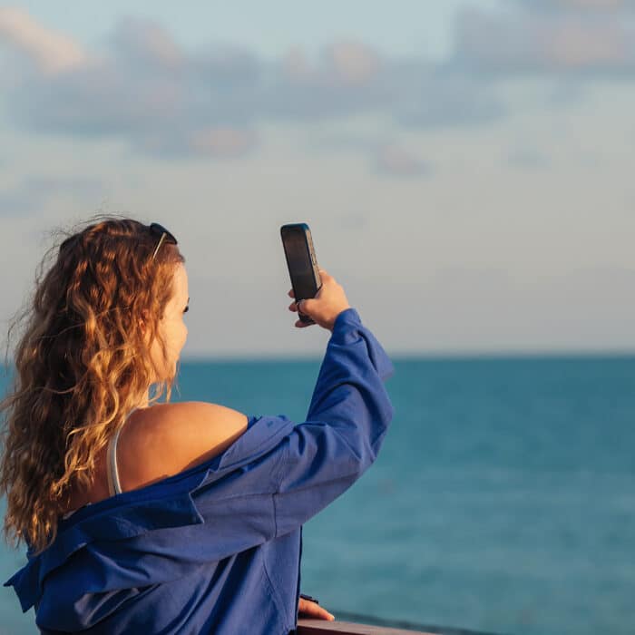 Blogger girl takes pictures of the sea on a phone camera