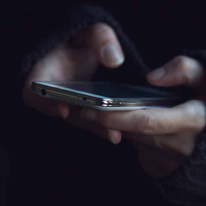 Close up of woman in dark sweater hands holding a phone